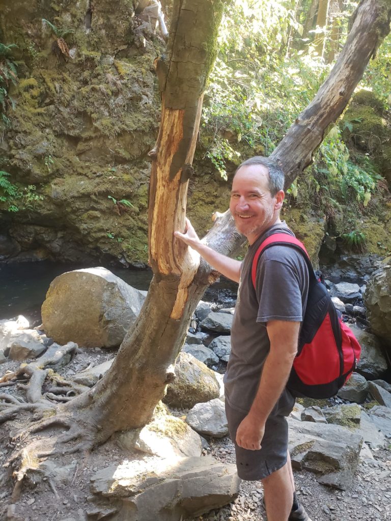 My brother posing with the wishbone tree in front of Hole in the Wall Falls, on the Starvation Creek trail.